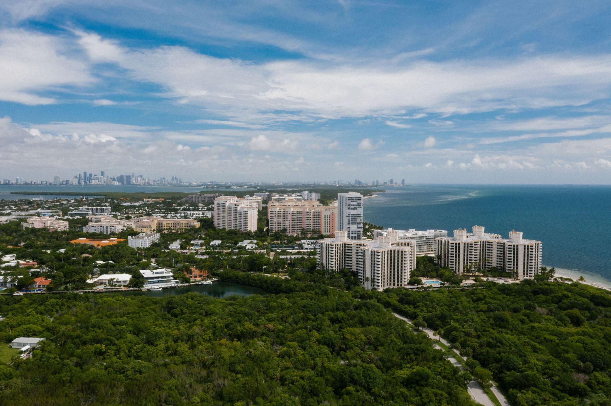Mid-rise condo buildings among trees beside the ocean