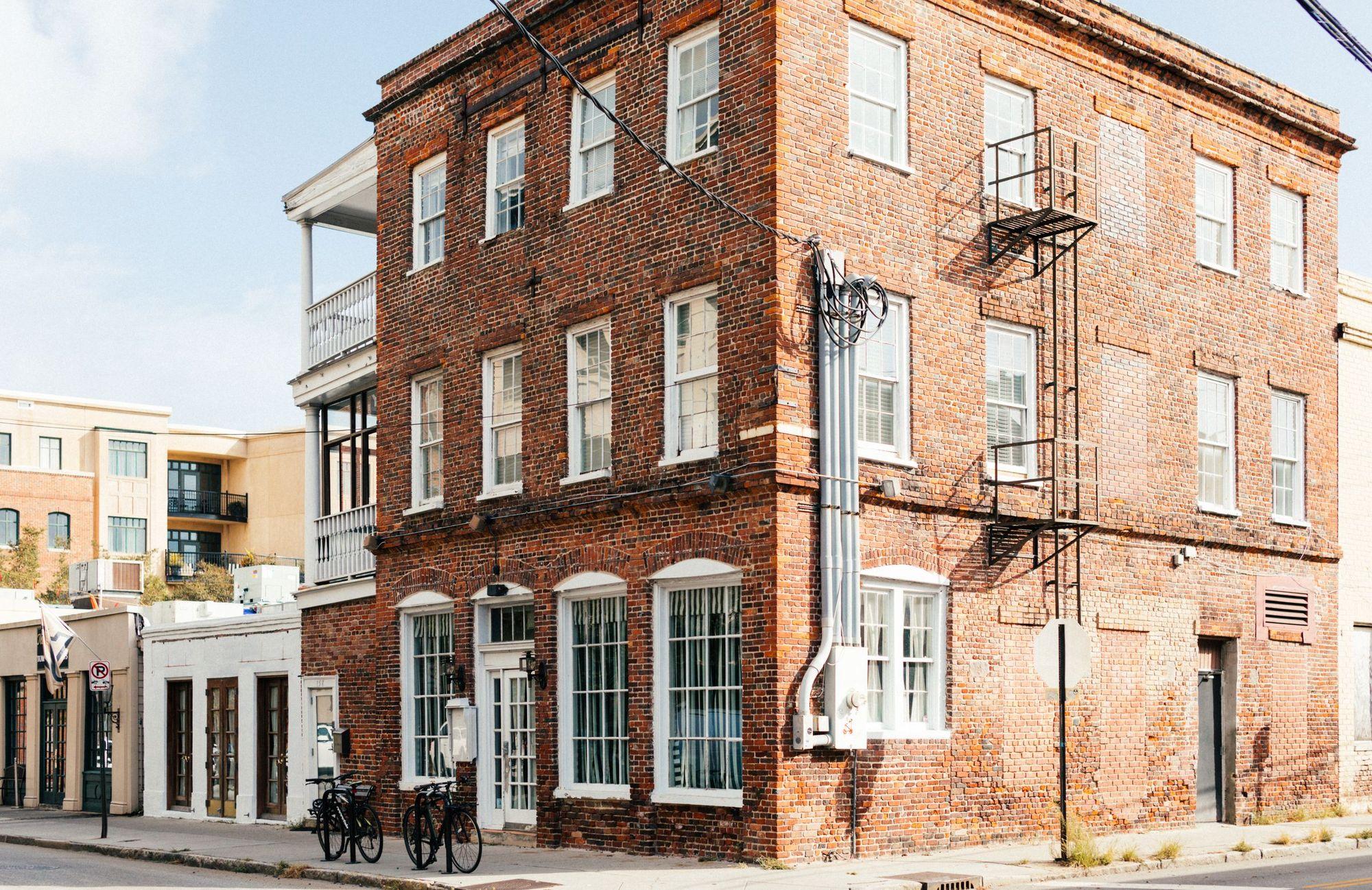 A three-story brick corner building with arched shopfront windows and apartments above