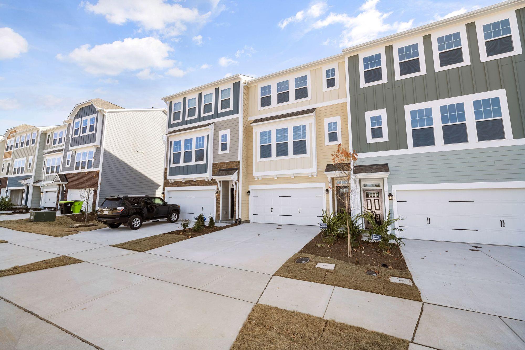A row of attached three-story townhomes with garages in a suburban community