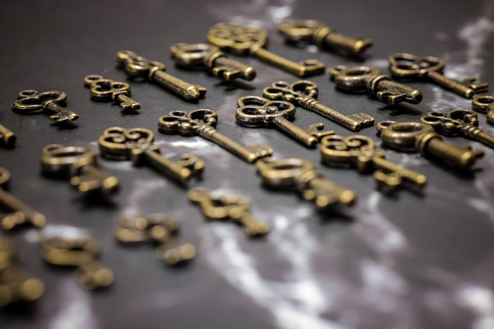 Rows of vintage brass keys laid out on a dark marble surface