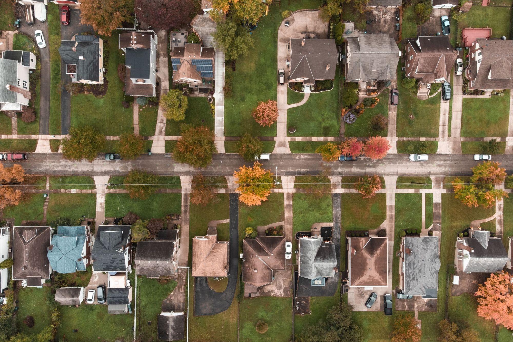 Aerial view of a residential street lined with older single-family homes and autumn trees